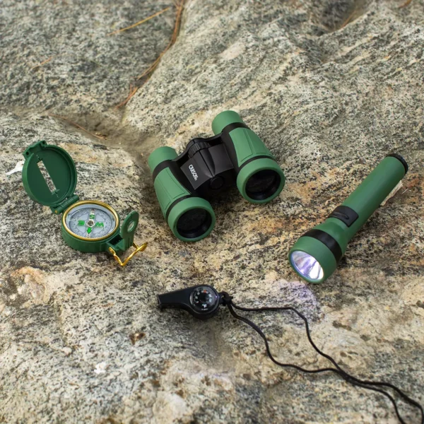El Kit infantil de exploración 5 en 1 Carson HU-401 | La serie AdventurePak™—con prismáticos, brújula, silbato, linterna y mochila—está dispuesta sobre una gran roca texturizada, ideal para pequeñas aventuras STEM.